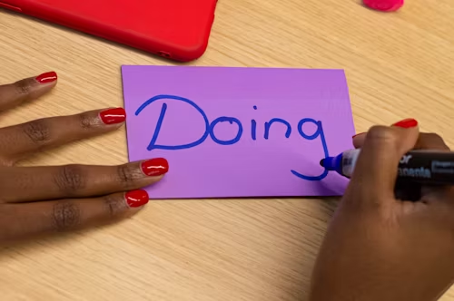 Purple post it card with the word Doing written