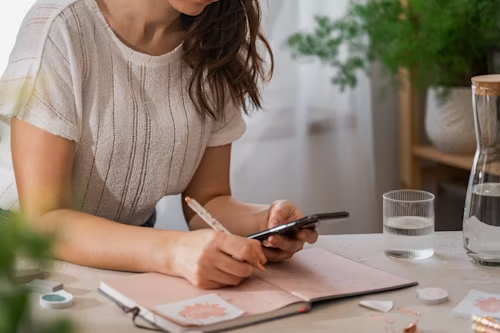 A person looking at the phone while holding a pen