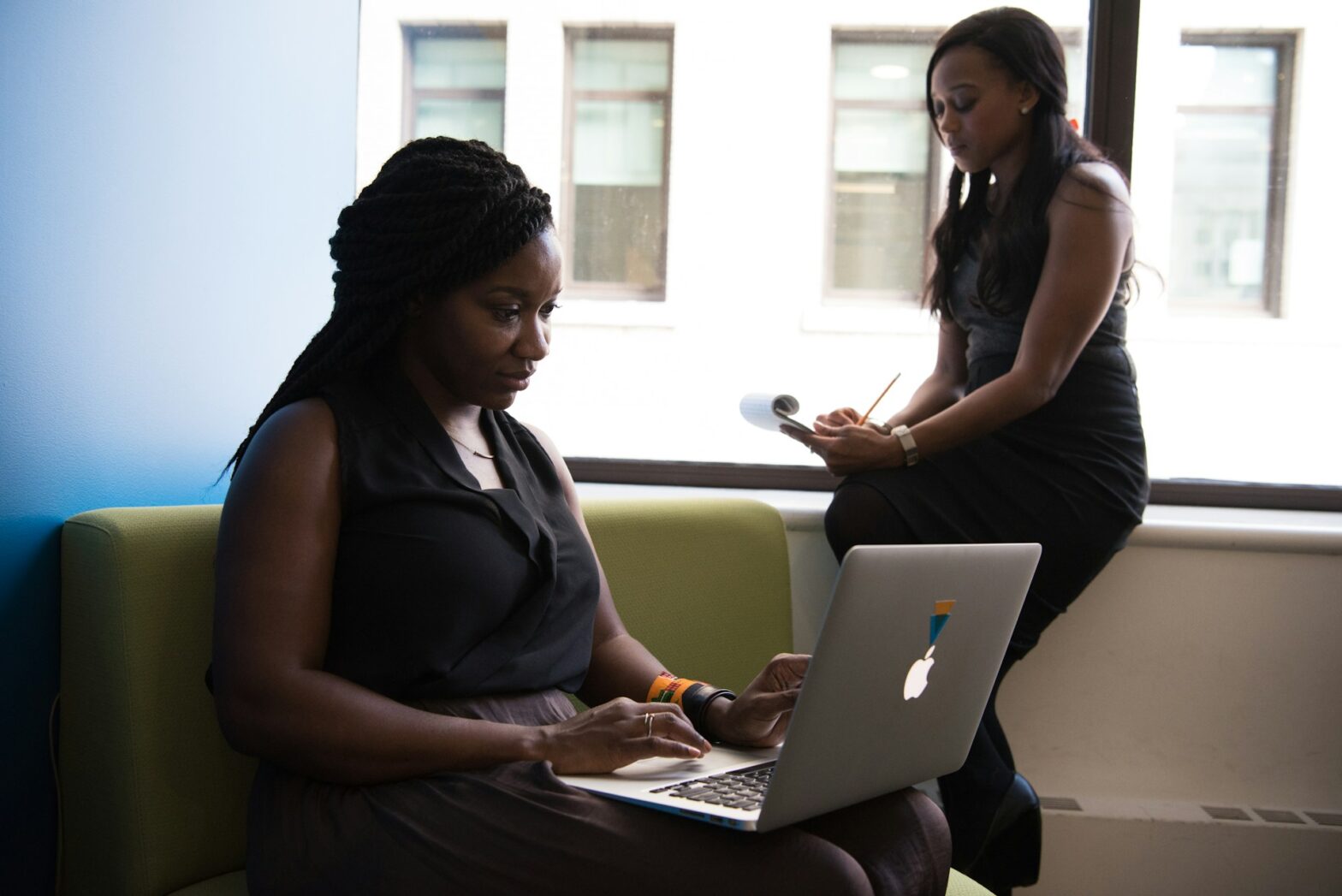 Two woman holding a laptop and a phone