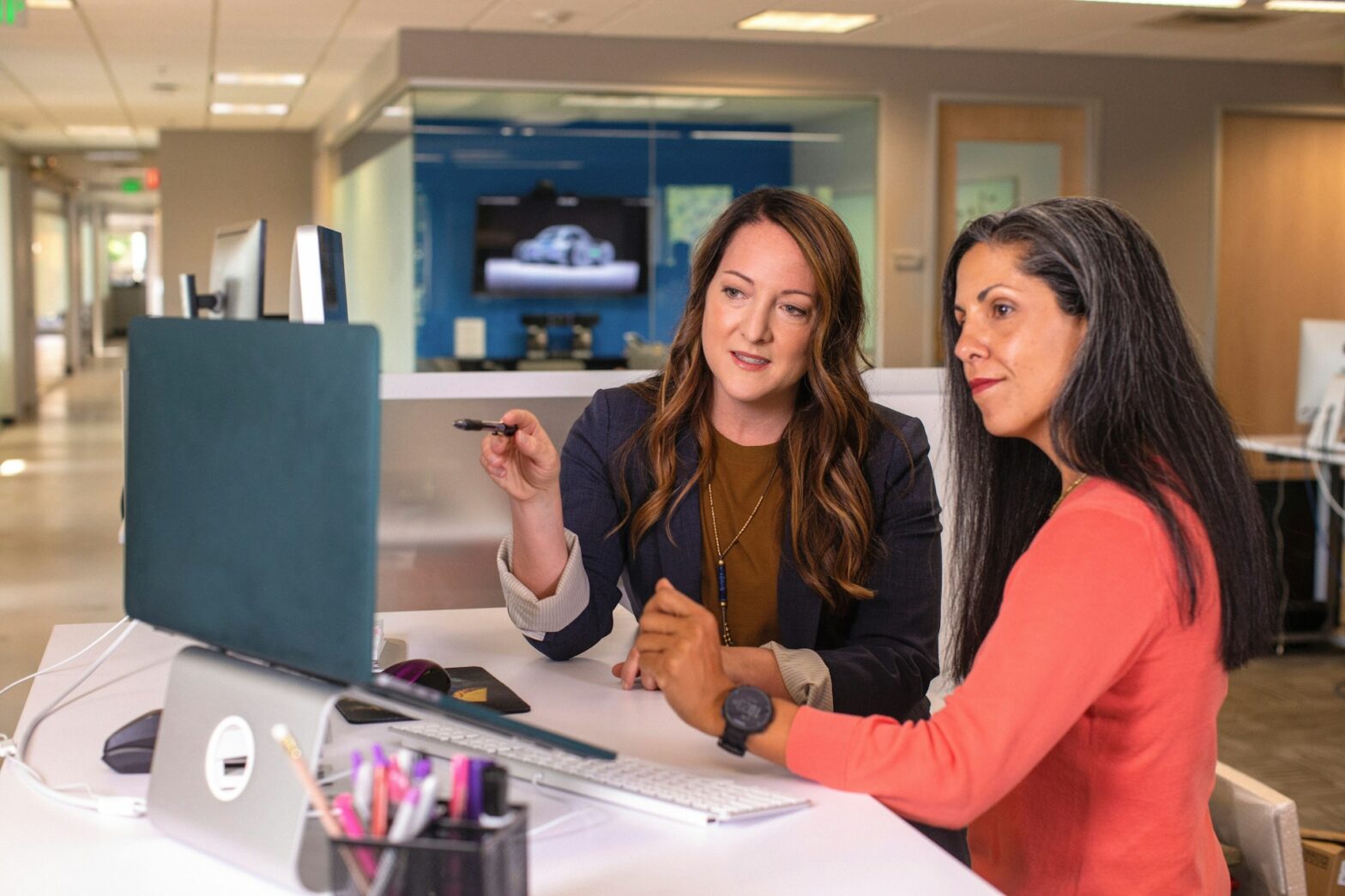 Two women pointing at a computer screen