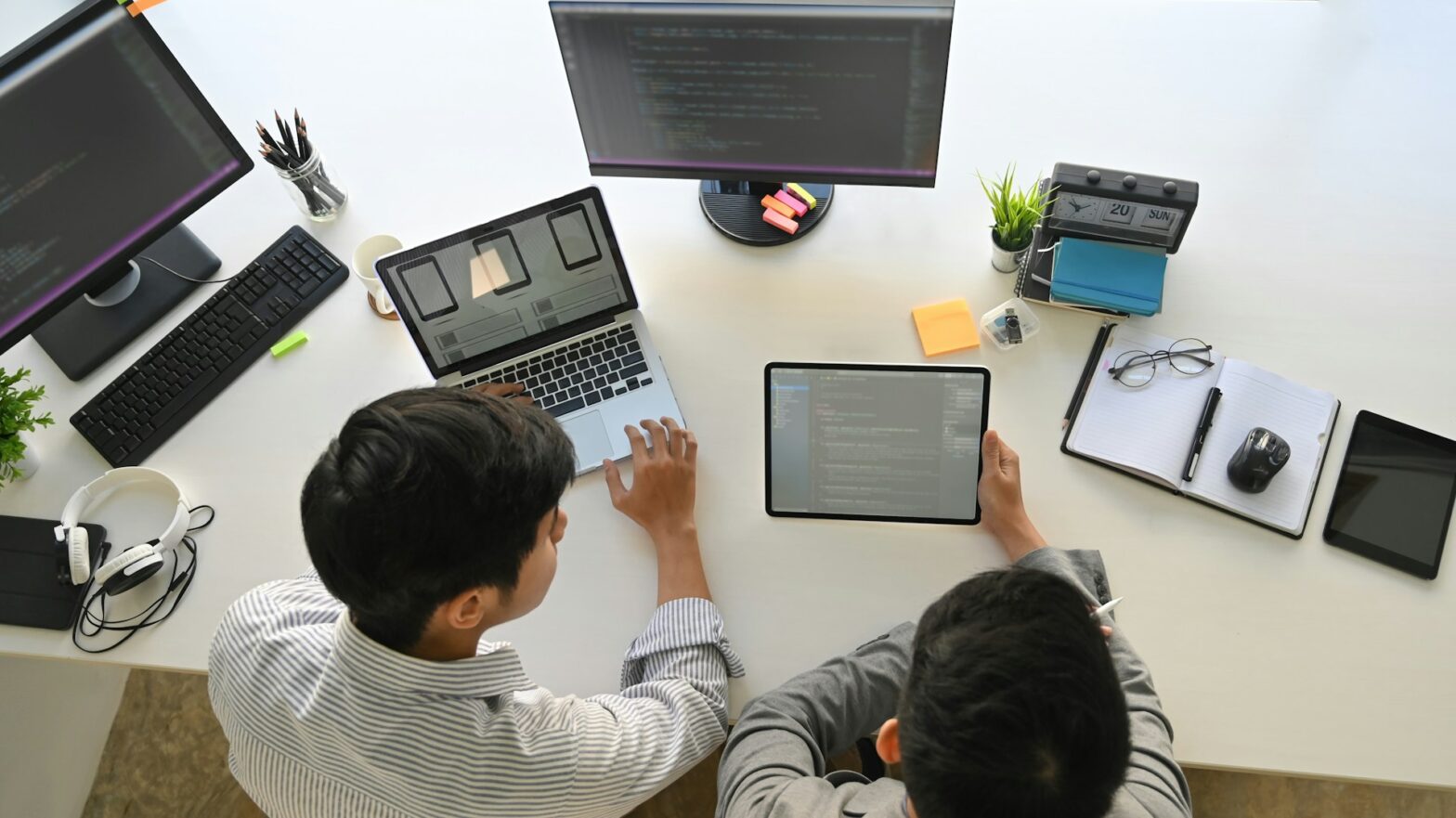 Two people with a laptop and an ipad